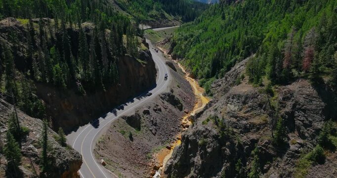 High angle aerial of narrow mountain highway hugging steep canyon walls in Colorado, Million Dollay Highway Colorado USA