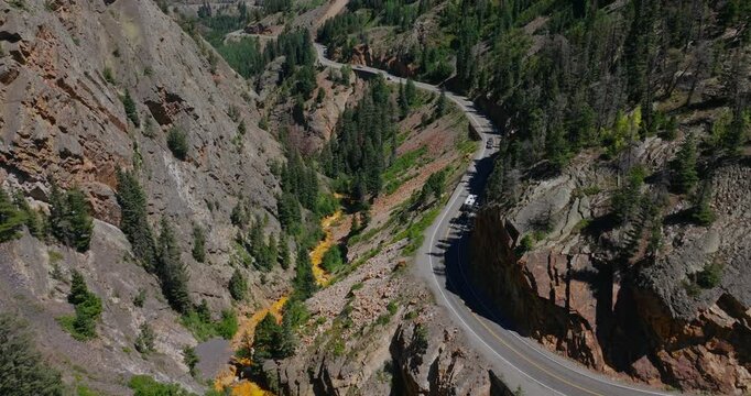 High aerial of mountain roadway clinging to steep slopes above alpine canyon, Million Dollay Highway Colorado USA