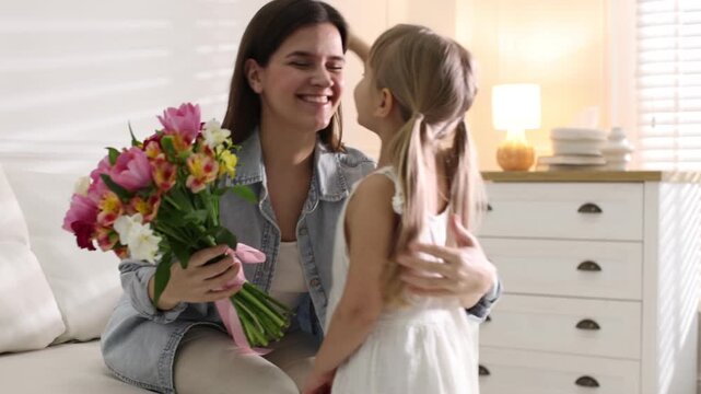Happy Mother's Day. Little girl greeting her mom with bouquet of beautiful flowers at home. Camera moving forward