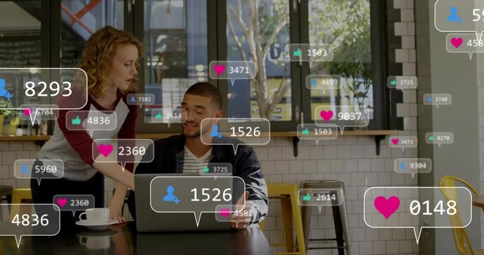 Server placing cup while customer viewing laptop in cafe, social media likes rising, checking reach