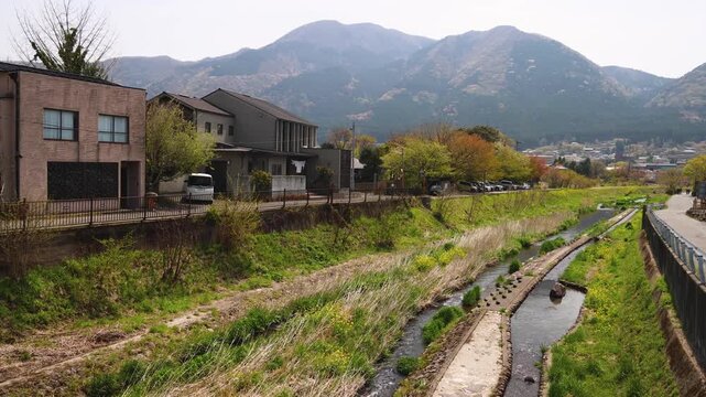 Yufuin town, Oita prefecture, Japan, hot spring onsen resort town, with mount Yufu, Yunotsubo pedestrian shopping street, Kyushu island region, rural mountain landscape, a spring day with a blue sky