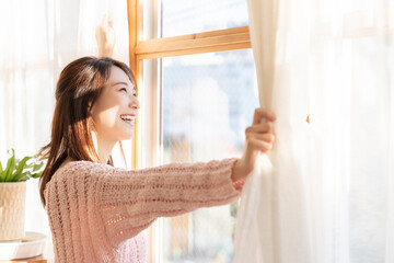 カーテンを開ける女性