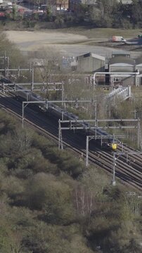 Vertical aerial view of train going down track in England, United Kingdom. Public transportation and commuting concept