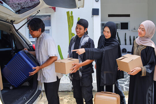 Muslim Family Loading Luggage and Boxes into Car for Travel During Eid Celebration