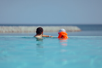Father and Daughter Vacationing at the Infinity Pool. Happy family enjoying a premium summer vacation at a luxury resort infinity pool with a scenic horizon view 