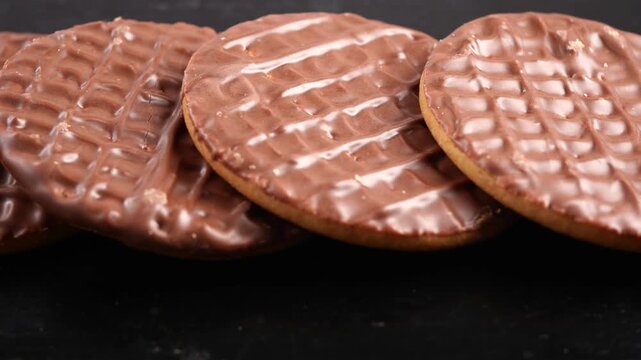 Enjoying chocolate covered cookies on a dark table