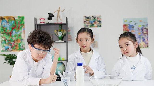 Young Asian Students in Lab Coats Conducting Science Experiment in Classroom