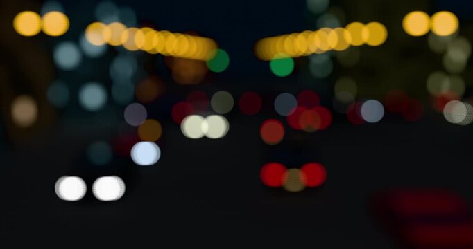 Abstract view of blurred city light of cars. Defocused red lights from moving traffic on a night cityscape. Round colorful bokeh effect on a urban black background. 4K 3D rendering loop animation.