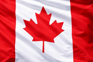 Obraz premium Canadian flag waving gently, showcasing the iconic red maple leaf centered on white fabric with vivid red sides. Bright lighting reveals texture, pride, and patriotism.