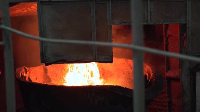 Molten Metal Pouring. Interior Of Glowing Furnace With Molten Metal Pouring Into Crucible From Ladle . Stock clip