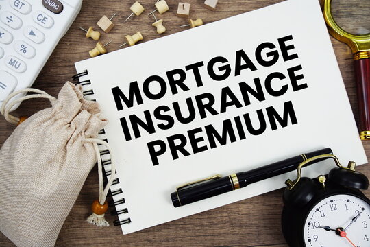 Mortgage Insurance Premium text written on notepad with pen, alarm clock, magnifying glass and calculator on wooden background
