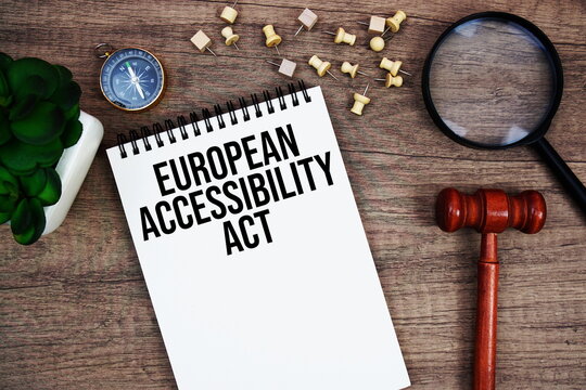 European Accessibility Act message written on notepad with wood gavel and magnifying glass flat lay on wooden background