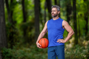 Professional basketball player training outdoor. Guy has sport motivation. Sport and hobby. Sport and recreation. Active lifestyle. Summer activity. Man with basketball ball in forest, copy space © be free