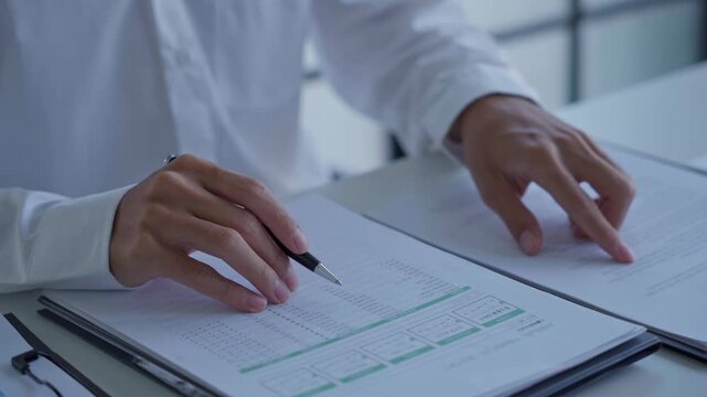 Businessman holding pen checking document on working desk