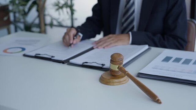 Lawyer holding pen checking documents with gavels on desk