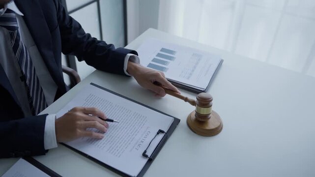 Lawyer holding pen checking documents with gavels on desk