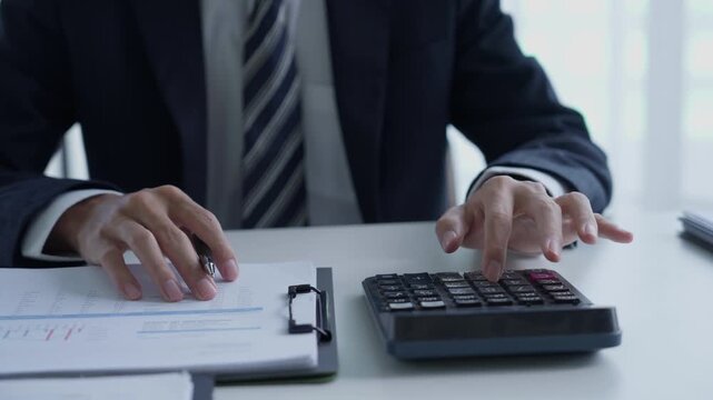 Accountant in suit do accounting and pressing calculator