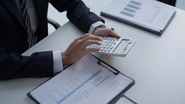 Accountant in suit do accounting and pressing calculator