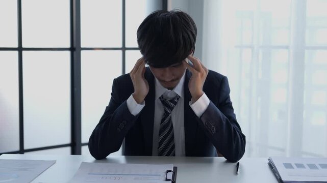 Stressed businessman holding head hard working in office