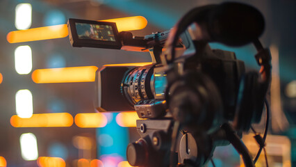 Professional Video Camera on Tripod Filming Event with Bright Bokeh Lights and Copy Space © Aliaksei