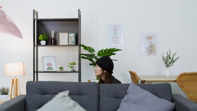 Asian Female Thief in Beanie Rummaging Through Living Room During Burglary