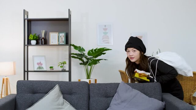 Asian Female Thief in Black Costume Stealing Money in Living Room