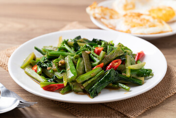 Stir-fried Chinese kale with soy sauce served with a fried egg on a white plate, Thai food style