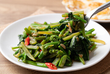 Stir-fried Chinese kale with soy sauce served with a fried egg on a white plate, Thai food style