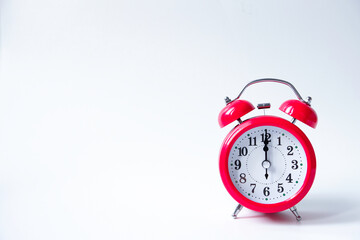 The classic red alarm clock is isolated on a white background