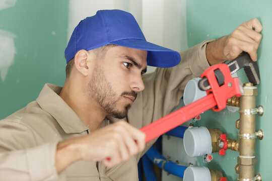 male plumber fixing water meter with adjustable wrench