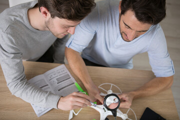 two men are assembling a drone at home
