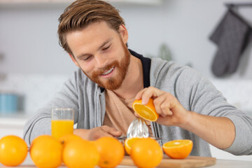 healthy handsome man making organic orange fruit juice