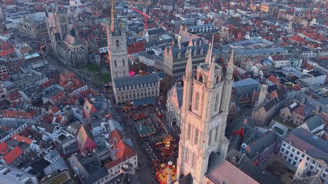 Drone footage of the Christmas square in front of Saint Bavo&rsquo;s Cathedral in Ghent, gradually revealing the illuminated cityscape with festive holiday decorations and medieval architecture.