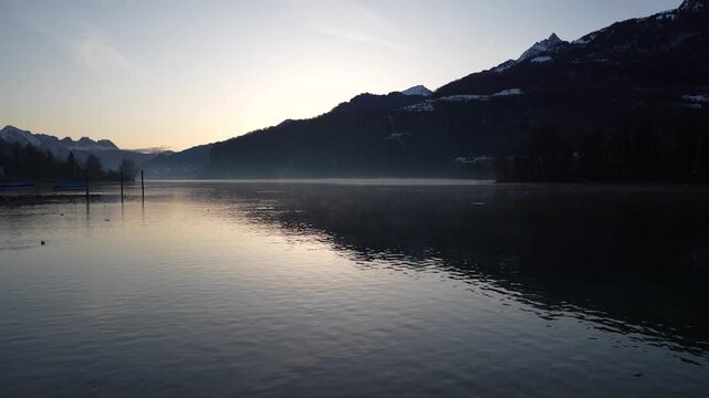 Calm morning view of Walensee lake with soft mist and mountain silhouettes