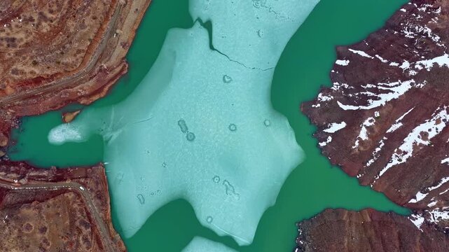 Aerial Top View of Frozen Lake with Turquoise Water and Melting Ice Patterns