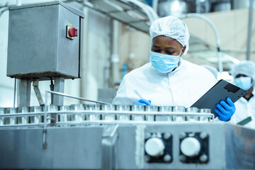 Manufacturing supervisor checks batch of canned food products on assembly line while following...