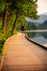 Woman running by the lake on a sunny day. Active lifestyle and outdoor fitness concept.