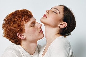 Man and woman in close embrace with peaceful expression, showing intimacy and connection in studio setting against plain background. Couple portrait with soft lighting and relaxed mood.