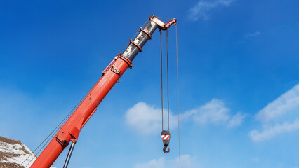 Crane lifting materials at construction site under blue sky