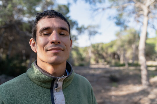 Young man meditating eyes closed in nature forest