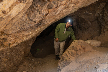 Person exploring dark cave with headlamp for adventure