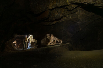 Woman exploring dark underground cave with headlamp