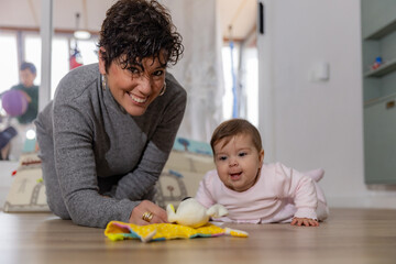 Fototapeta premium Mother and baby playing on floor with toy