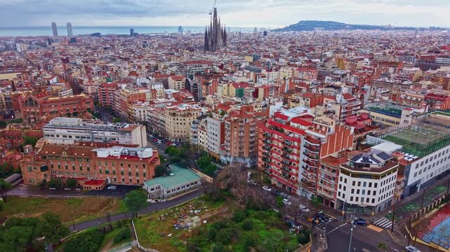 Eixample district and urban skyline with the iconic Sagrada Fam&iacute;lia in Barcelona, Spain. Aerial backward