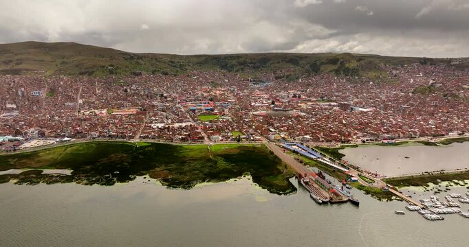 Wide drone view of vast Puno city with dense construction on Lake Titicaca shore