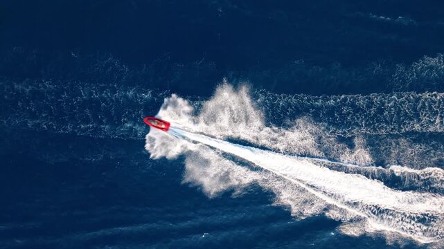 Red speedboat racing fast on open ocean, leaving white trails behind