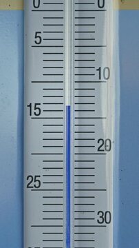 Vertical zoom in closeup of glass thermometer showing minus 15 celsius degrees , freezing cold winter temperature concept