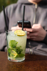 relaks osoby trzymającej w dłoniach smartfon, przy drinku mojito © siwyk