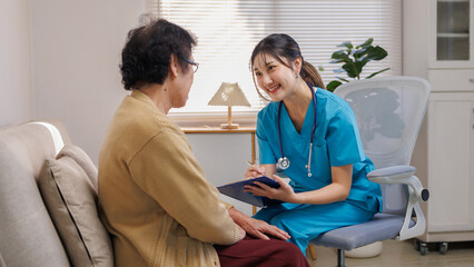 Asian nurse having a conversation with a senior woman at home, providing dedicated elderly care and...