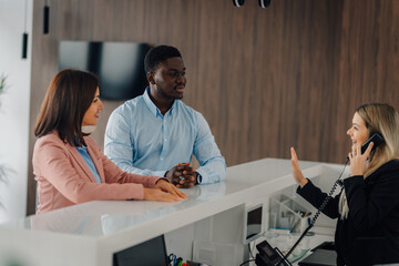 Diverse customers interacting with hotel reception desk staff